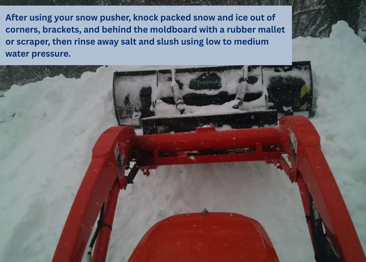 Image of tractor using snow pusher, taken from the drivers viewpoint. After using your snow pusher, knock packed snow and ice out of corners, brackets, and behind the moldboard with a rubber mallet or scraper, then rinse away salt and slush using low to medium water pressure.